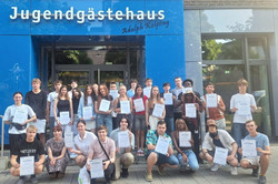 Gruppe steht mit Teilnahmebescheinigungen vo dem Jugendgästehaus.