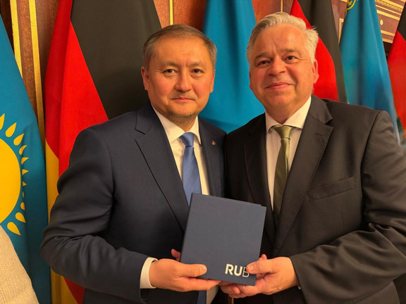 RUB-Kanzler Achim Dilling (rechts) und der kasachische Wissenschaftsminister Sayasat Nurbek. Hinter ihnen stehen deutsche und kasachische Flaggen.