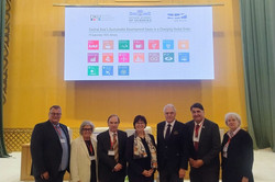 Das neueste Bild zeigt eine Gruppe von sieben Experten (vier Männer und drei Frauen) in formeller Kleidung, die vor einer großen Leinwand in einem prunkvollen, goldgetäfelten Saal in Almaty posieren. Die Präsentation trägt den Titel „Central Asia’s Sustainable Development Goals in a Changing Global Order“ und zeigt die Logos der Deutsch-Kasachischen Universität (DKU), der Nationalen Akademie der Wissenschaften und der UA Ruhr sowie die 17 UN-Nachhaltigkeitsziele.