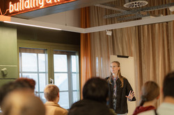A person speaks to a group of listeners in an event room at the BRYCK Startup Alliance. Above the scene, the words ‘building a livable future’ are illuminated.