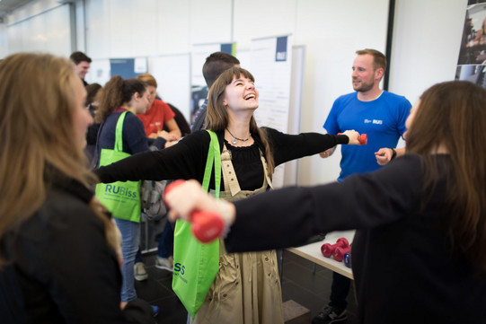 A student holds a small weight and laughs at the RUB fitness stand.