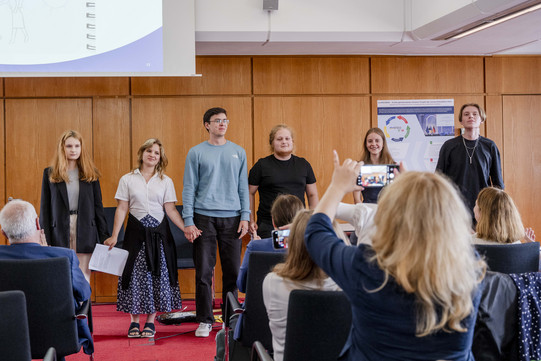 Auftakt mit Lesung In einer szenischen Lesung im Senatsaal der RUB stehen einige Studienernde und präsentieren ein Projekt.