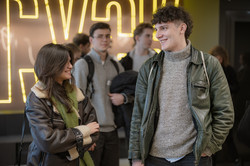 Two participants at the Studienbrücke alumni meeting chat in front of a bright ‘BRYCK’ sign, with other people standing in the background.