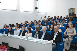 Ein Hörsaal der East Kazakhstan Technical University (EKTU) mit zahlreichen Teilnehmenden. Vorne sitzen drei Referentinnen an einem Podium, hinter ihnen sind Präsentationsfolien auf einer Leinwand und einem Bildschirm zu sehen. Banner der University Alliance Ruhr und der EKTU flankieren die Bühne, während das Publikum den Vorträgen aufmerksam folgt.