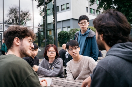 Neue Studierende sitzen am Tisch und unterhalten sich mit Alumni der Studienbrücke.